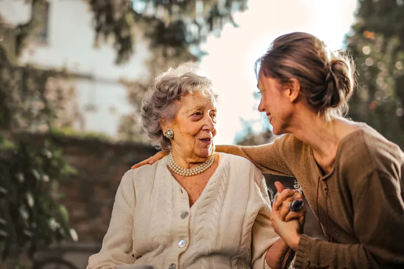 An older woman and a younger woman holding hands and smiling