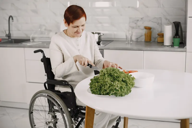 A woman in a wheelchair preparing vegetables in her kitchen