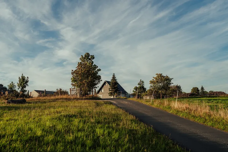 A country road leading to a farmhouse among green fields