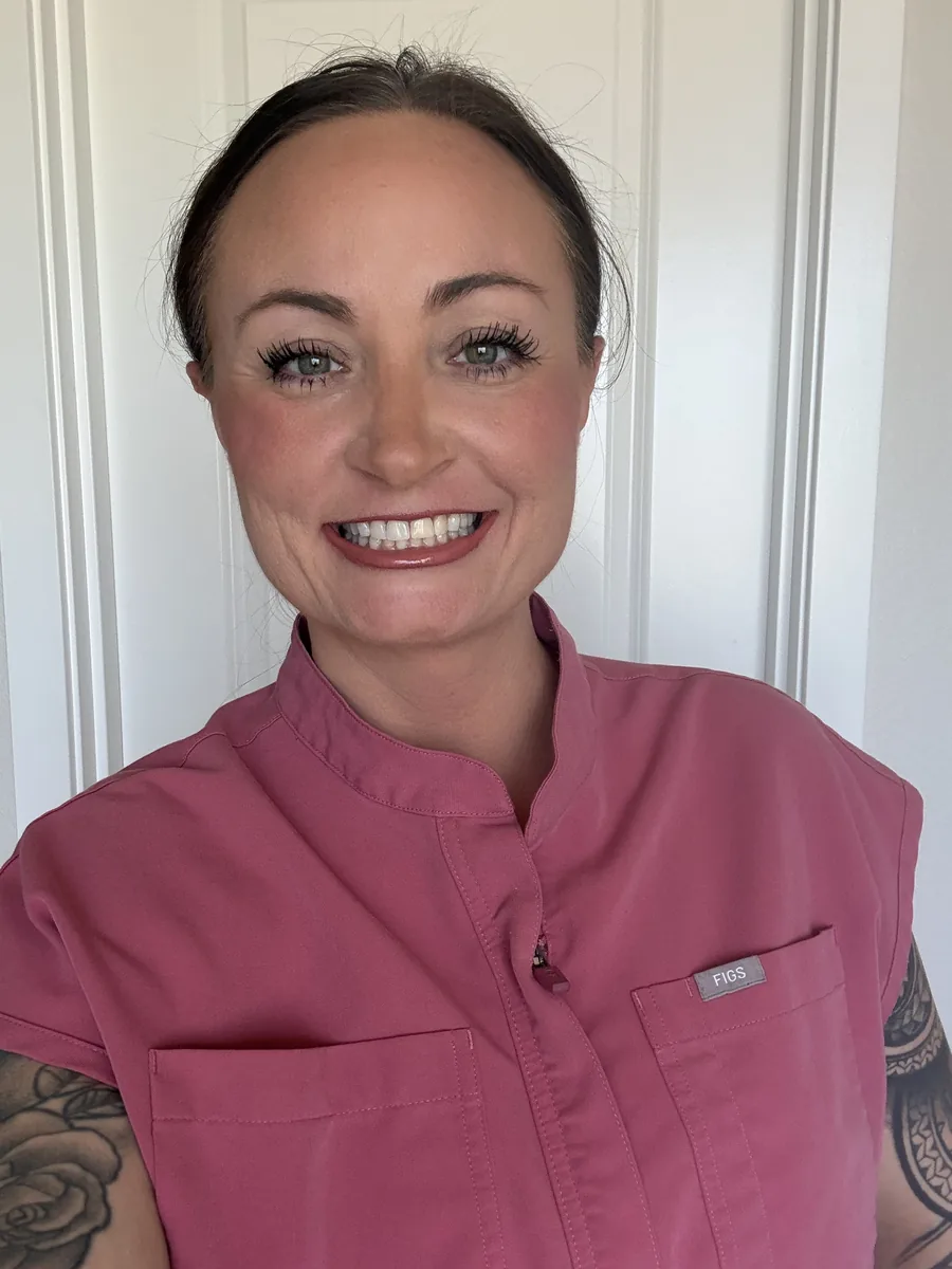 Jennifer Minnis smiling, wearing rose-colored scrubs